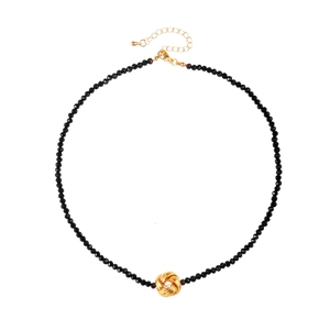 Élégant collier de perles noires avec pendentif noeud doré torsadé sur fond blanc