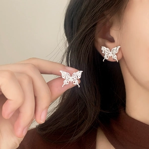 Elegant hollow butterfly stud earrings with delicate lace texture on model in silver