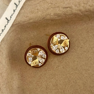 Macro shot of red resin earrings with gold butterfly inlay and sparkling zircons