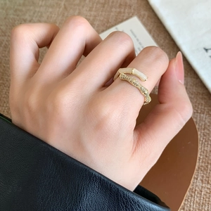 Gold bamboo joint open ring featuring white enamel and pavé crystals on finger