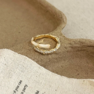 Detail of bamboo joint gold ring with cream enamel and sparkling cubic zirconia stones