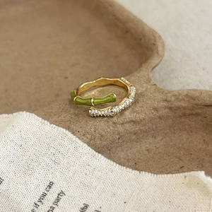 Detail of bamboo style gold plated ring with green enamel and sparkling zircon inlay