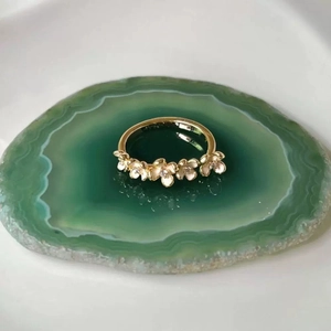 Elegant gold flower ring featuring five white enamel blossoms with crystals on green agate