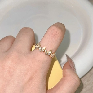 Elegant gold butterfly ring with white enamel and sparkling zircon stones on finger