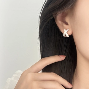 Elegant crossover earrings with pave zircon and white enamel on female model