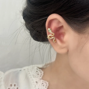 Golden snake ear cuff with white and green cubic zirconia on model wearing white lace