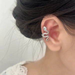 Silver snake-shaped ear cuff with zircon pave and green gem eyes worn by a model