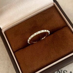 Détail d'une bague fine dorée avec perles et zircons dans un écrin en velours chic