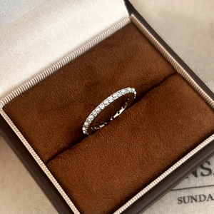 Macro d'une bague en perles et diamants argentés dans un écrin en velours marron