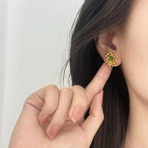Elegant gold flower stud earrings with green zircon center on model side view