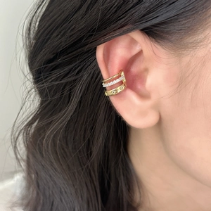Detail of a triple-layered gold ear cuff featuring sparkling cubic zirconia stones
