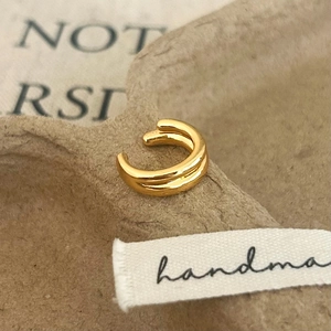 Detail of minimalist gold double-layered ear cuff on a vintage textured background