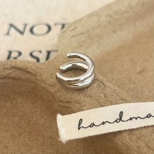 Detailed view of silver double-layered ear cuff on a textured handmade paper tray