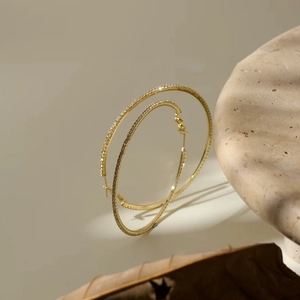Detail of large gold hoop earrings featuring micro-set white cubic zirconia stones