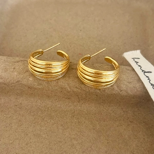 Macro detail of textured gold C-shaped earrings with parallel horizontal ribbing