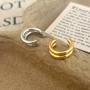 Bagues d'oreilles minimalistes à double couche en argent et or sur un plateau texturé