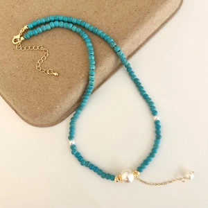 Detail of beaded necklace with blue turquoise, white pearls and gold lobster clasp
