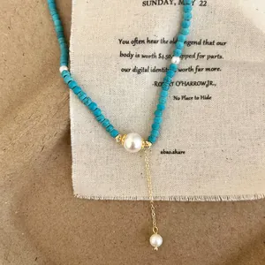 Detail of turquoise beaded necklace with large central pearl and gold chain pendant