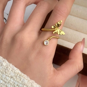 Elegant gold butterfly open ring with a dangling zircon stone shown on a hand