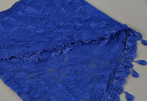 Macro detail of royal blue rose floral lace fabric and teardrop crochet tassels