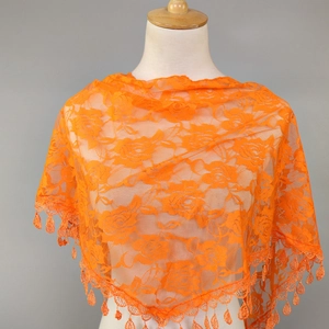 Macro detail of vibrant orange lace shawl featuring delicate floral patterns and tassel edges