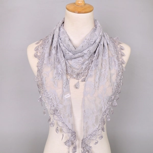 Close-up of light grey lace triangular scarf with rose hollow patterns and tassel fringe