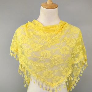 Detail of bright yellow lace shawl with rose floral patterns and delicate fringe tassels