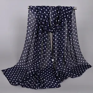 Dark blue chiffon scarf with white polka dots hanging on a metal rack display