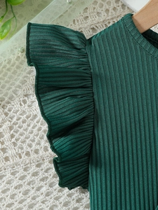 Detail of dark green ribbed knit bodice with elegant ruffle sleeves on hangers