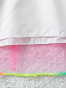 Detail van de witte stof en roze tule zoom op de eenhoorn jurk voor meisjes