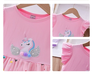 Détail de broderie licorne avec paillettes et pompons sur la robe rose fille