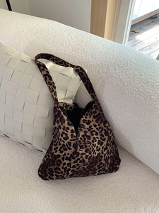 Detail of corduroy leopard print tote bag texture resting on a white plush sofa