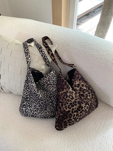 Detail view of corduroy leopard print tote bags in two colors on a white sofa