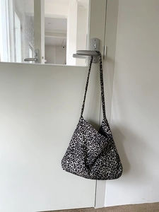 Detailed view of leopard print corduroy tote bag hanging on a minimalist white door handle