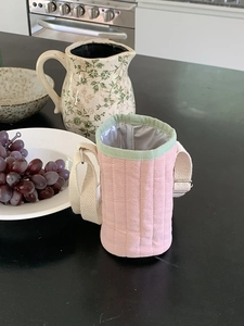 Dettaglio borsa termica trapuntata rosa per borraccia con bordo verde e tracolla bianca