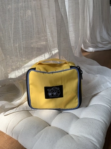Detail of yellow canvas makeup bag with blue trim and cute cartoon bear print