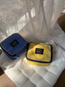 Detail of blue and yellow nylon travel cosmetic bags with cartoon bear patches