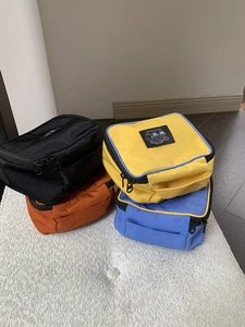 Detailed view of colorful nylon travel pouches with top handles and zippers on plush rug