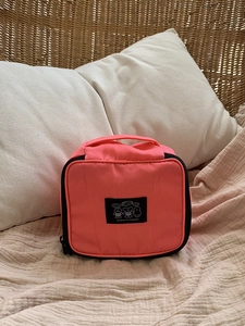 Detail of coral pink travel makeup bag with cartoon patch and sturdy black zipper