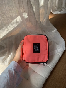 Detail of coral orange nylon makeup bag with bear patch and durable side handle