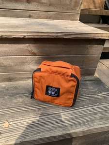 Detail of orange nylon cosmetic bag with hand strap and cartoon character graphic patch
