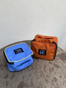 Detail of blue and orange portable nylon cosmetic bags with handles on a wood table