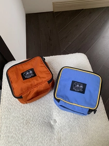 Detail of portable nylon cosmetic bags in orange and blue with side handles