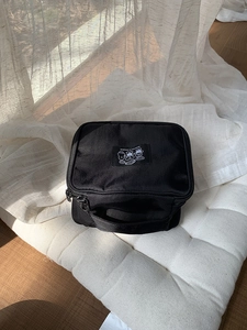 Portable black nylon travel cosmetic bag with sturdy handle and cute cartoon patch decoration