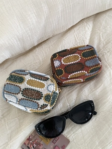 Detailed view of embroidered fabric coin purses in reddish brown and beige grey textures