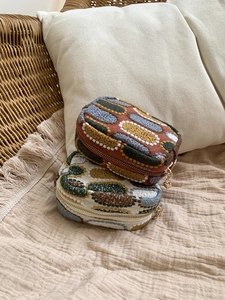 Detail of embroidered coin purses with heart zipper pulls on a woven texture background