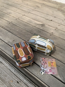 Detail of chenille zipper pouches with colorful jacquard patterns on wooden deck