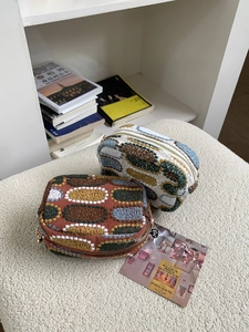 Detailed view of two embroidered mini pouches with colorful patterns and metal zippers