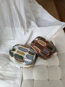 Detail of embroidered mini pouch with colorful geometric patterns and gold zipper