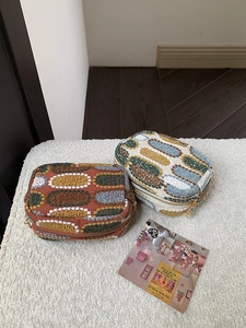 Detail of two woven mini pouches with colorful oval dot patterns and golden zippers